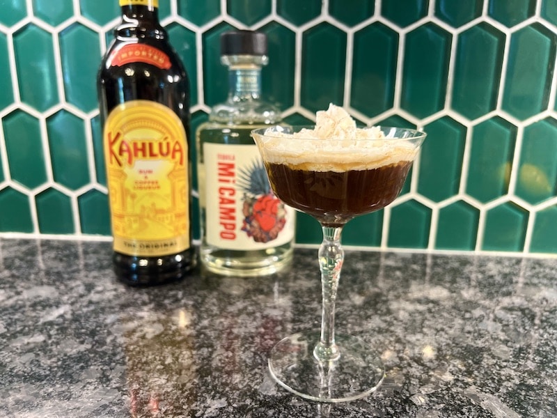 Mexican coffee cockatil with whipped cream and bottles of Kahlua and tequila