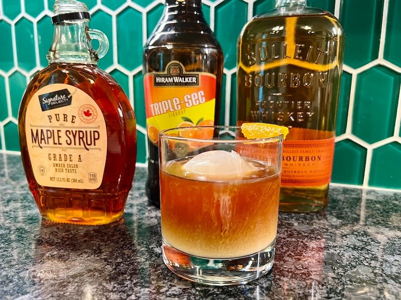cold brew coffee cocktail with maple syrup, triple sec, bourbon, orange peel garnish, ice ball