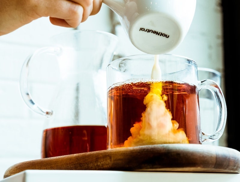 pouring coffee creamer into tea