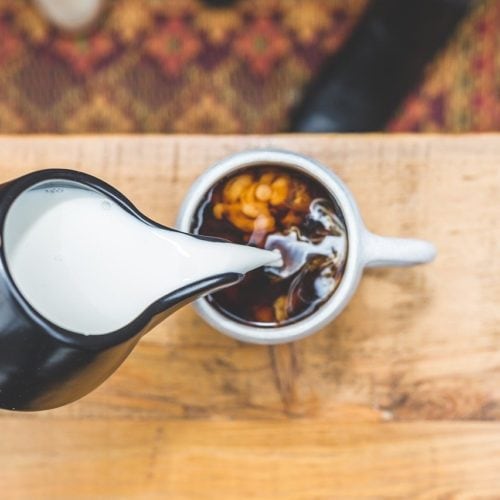 pouring creamer on coffee