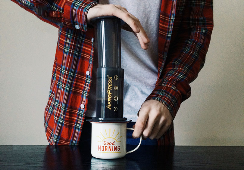 a person making coffee through aeropress