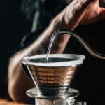 close up of a barista pouring boiling water into Kalita Wave Dripper to brew coffee