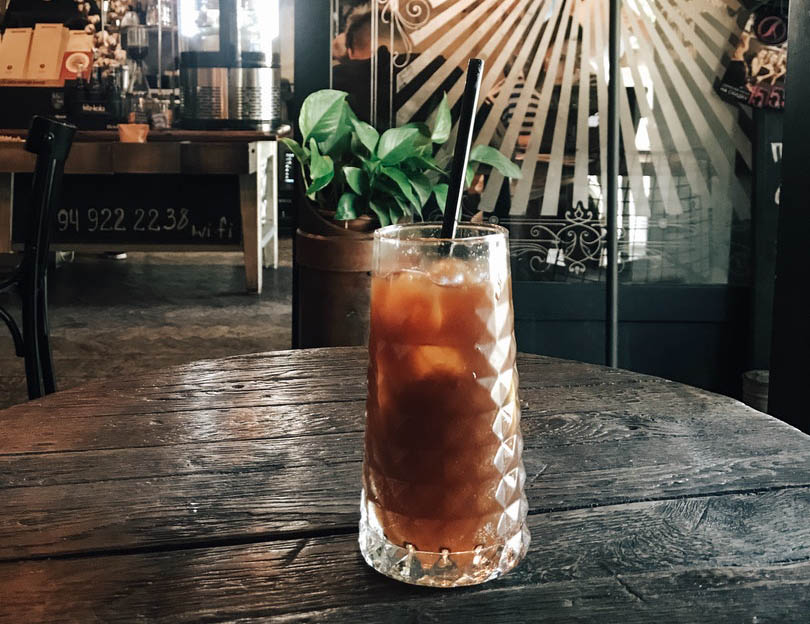 a tall glass of iced tea with black straw