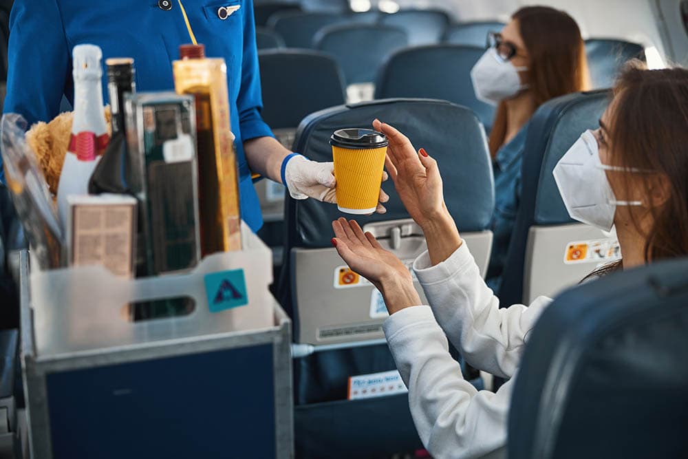 flight attendant handing over an airplane coffee to passenger