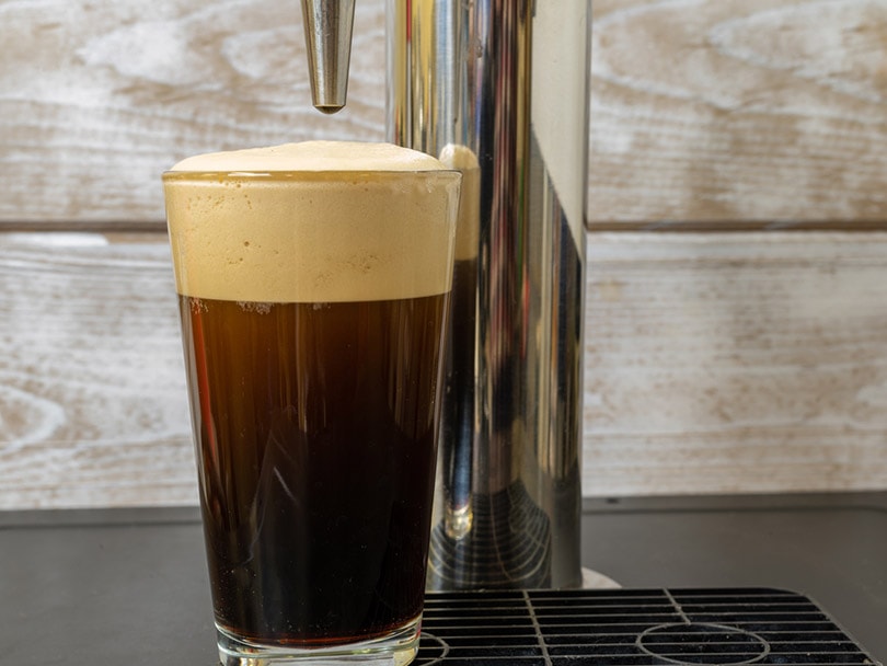 nitro cold brew coffee in a clear glass on a keg coffee dispenser