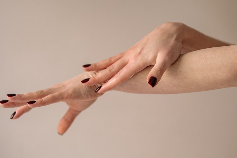 person with nail polish touching her arm