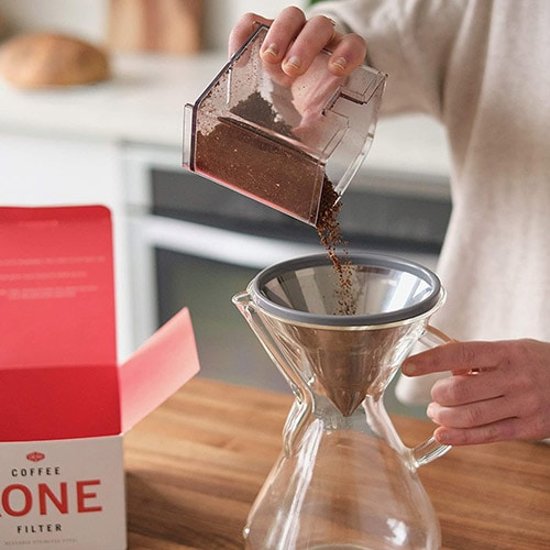 cropped woman pouring grind coffee into the kone filter