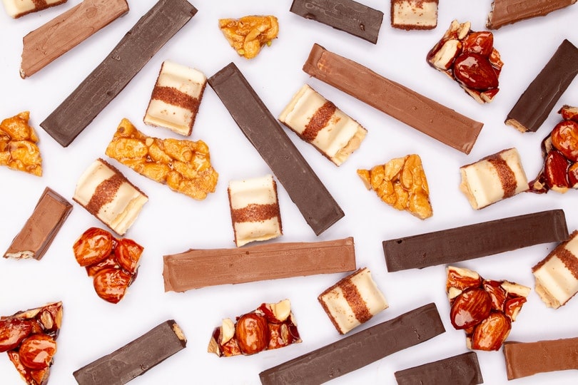 kit kat bars and caramel coated nuts on white surface