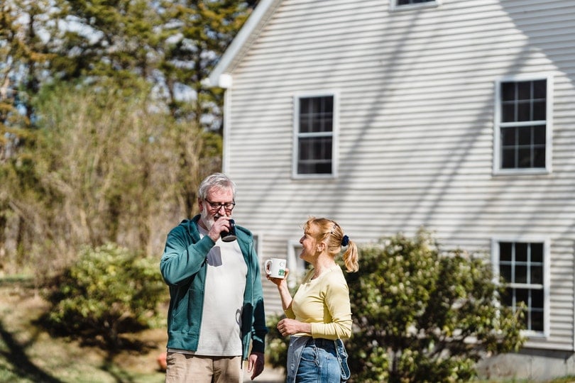 man and woman having coffee outside their house