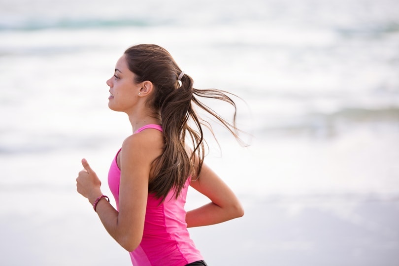 woman in pink shirt running by the sea