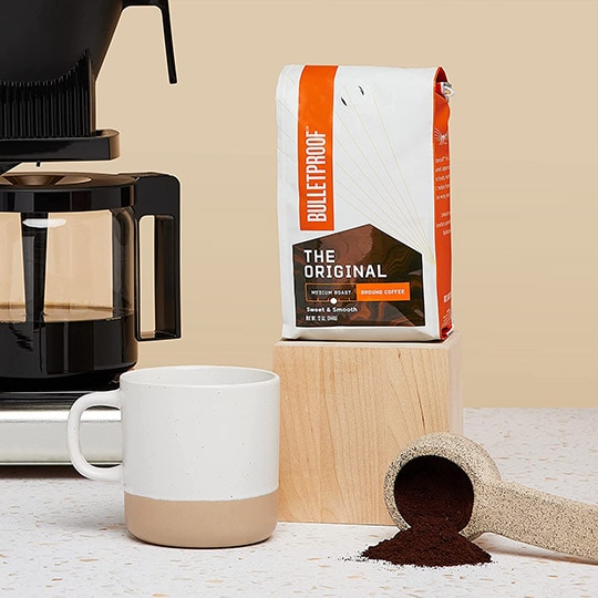 a bulletproof coffee original on a wooden box next to a cup coffee ground