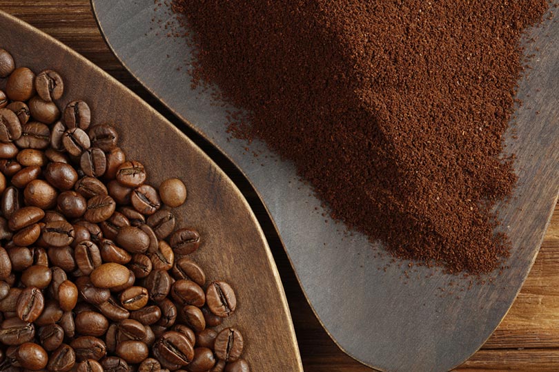 coffee beans and ground coffee on wooden plates