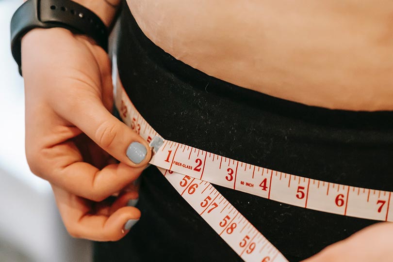 woman measuring hips with measuring tape