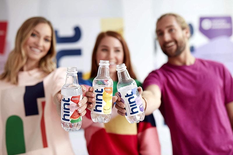 group of people holding bottles of Hint Water