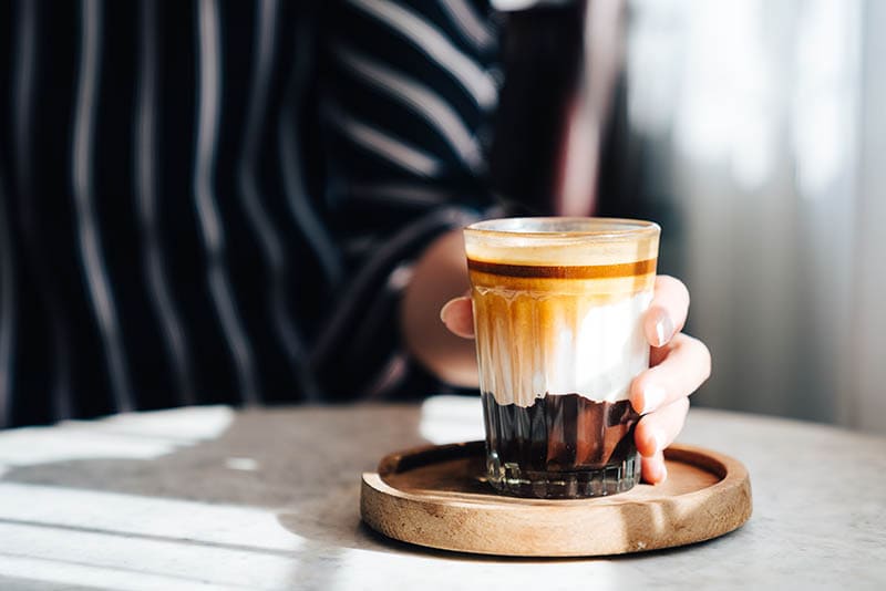 hand holding a glass of caffe marrochino