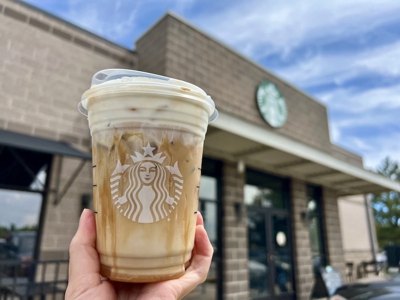 Starbucks caramel cloud macchiato with dark caramel sauce and cold foam outside cafe
