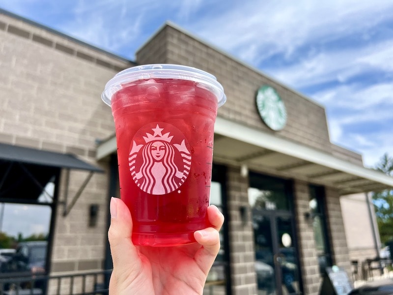 Starbucks iced passion tea drink with coffee shop in the background