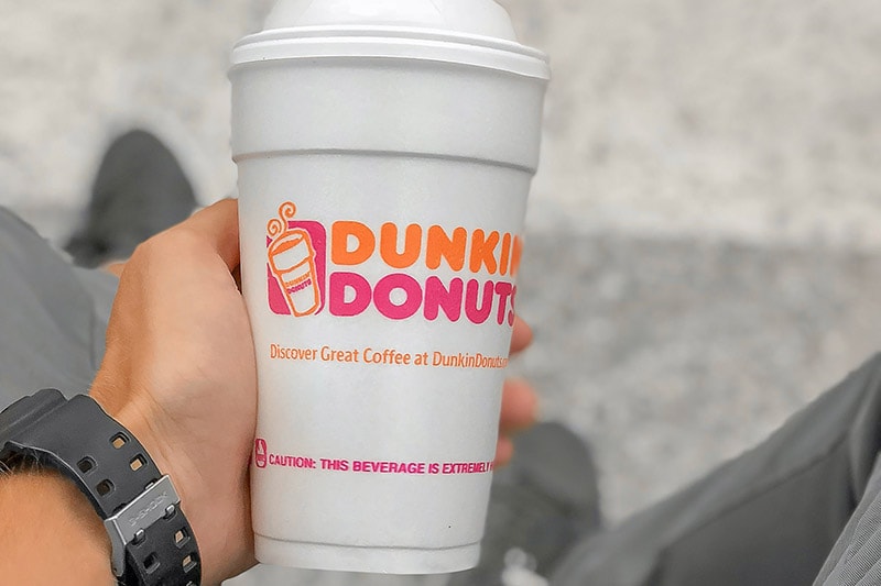 a man holding a dunkin donuts cup