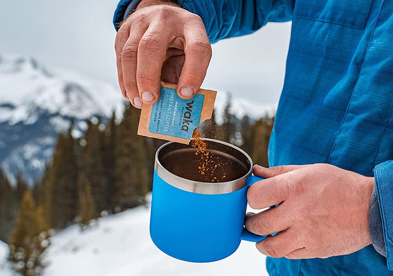 a man pouring waka colombian instant coffee into his mug