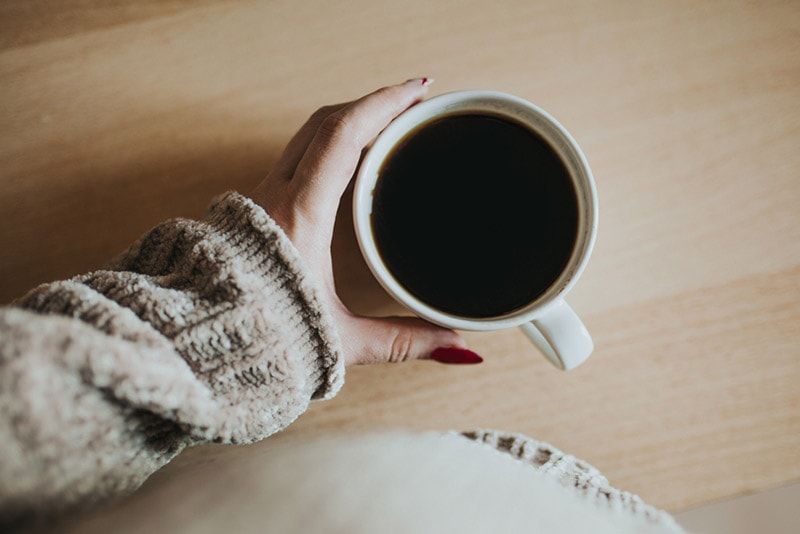 female hands picking up a cup of coffee